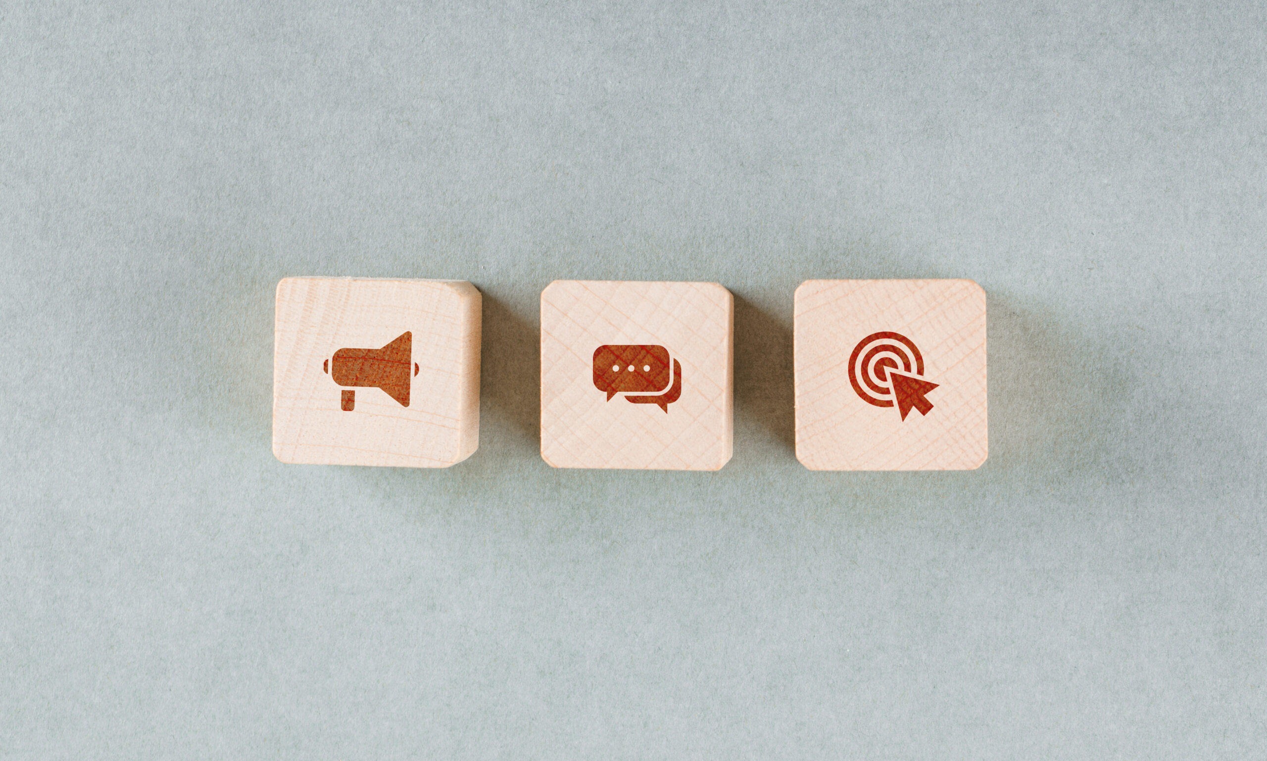 Conceptual of target with wooden blocks with red icons on sage color background flat lay. horizontal image